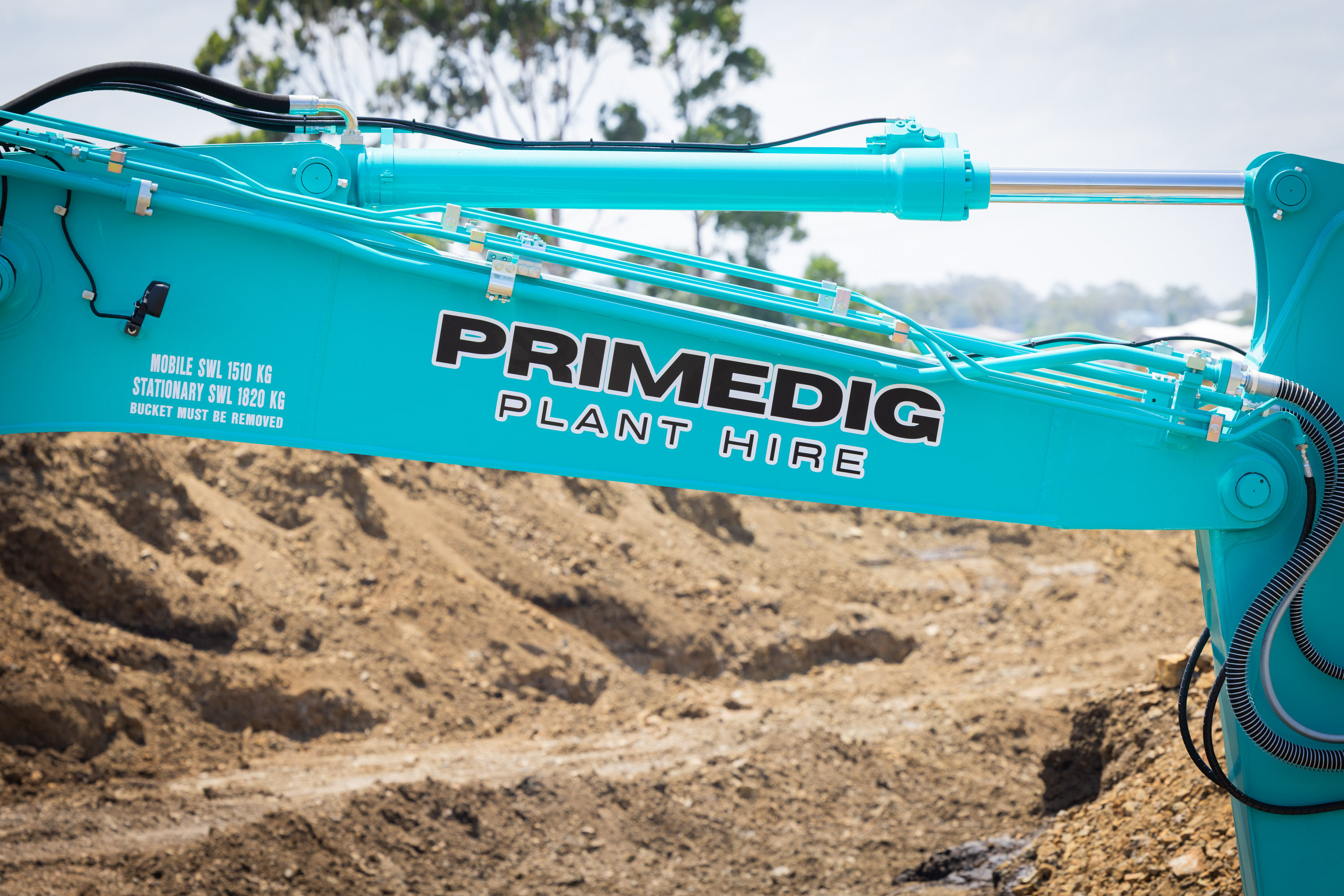 Kobelco excavator boom in PrimeDig livery over an earthworks site
